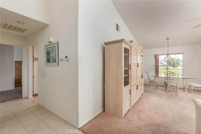 kitchen with light colored carpet, decorative light fixtures, and high vaulted ceiling