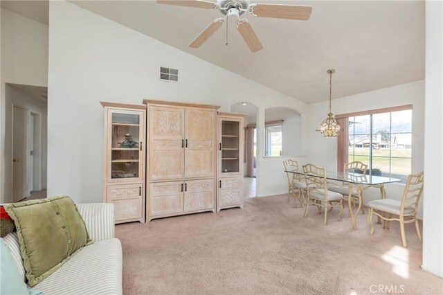 dining room with ceiling fan, light colored carpet, and high vaulted ceiling