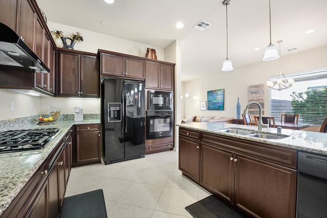 kitchen with sink, an inviting chandelier, pendant lighting, wall chimney range hood, and black appliances