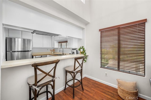 kitchen with sink, a healthy amount of sunlight, a breakfast bar, and stainless steel fridge