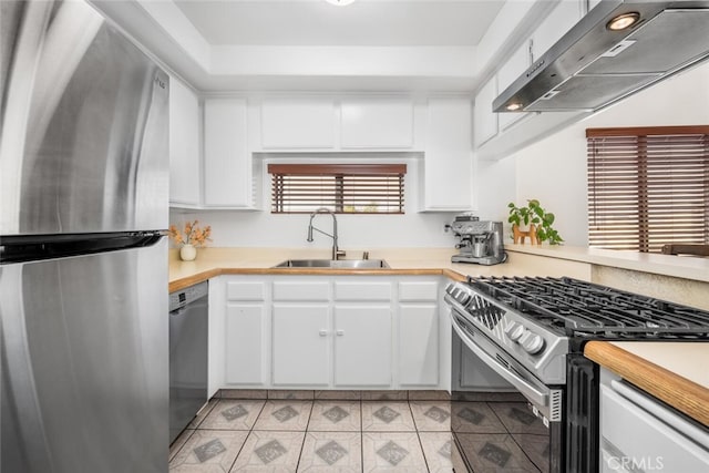 kitchen featuring appliances with stainless steel finishes, ventilation hood, light tile patterned floors, white cabinets, and sink