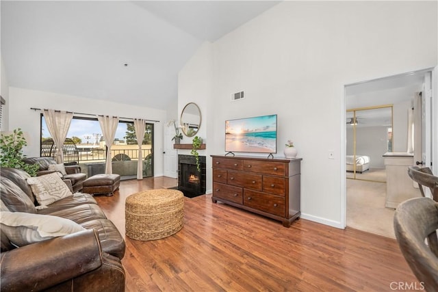 living room featuring ceiling fan, high vaulted ceiling, and hardwood / wood-style flooring