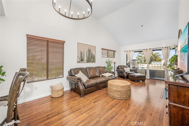 living room featuring high vaulted ceiling, hardwood / wood-style floors, and a notable chandelier