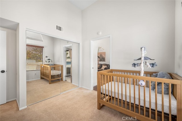 carpeted bedroom with a towering ceiling, a nursery area, and a closet