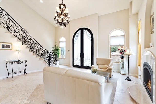 living room featuring a notable chandelier, french doors, a high end fireplace, and a high ceiling