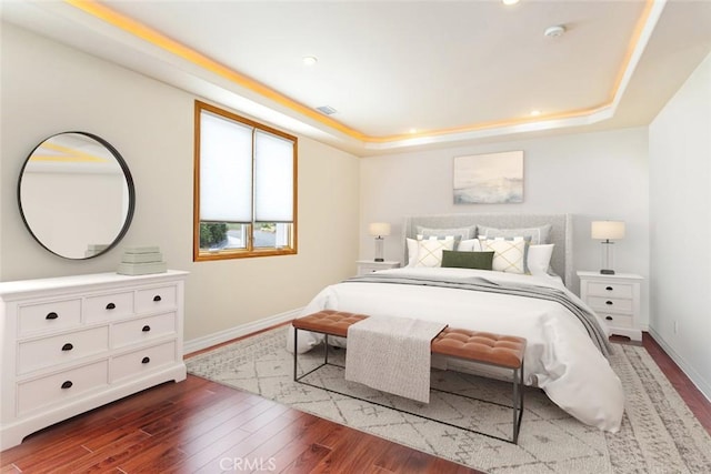 bedroom with a raised ceiling and dark hardwood / wood-style floors