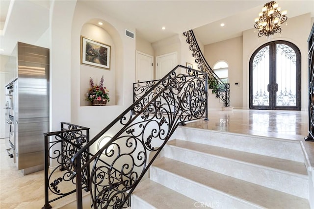 staircase featuring french doors and a notable chandelier