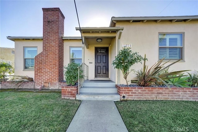 view of exterior entry with a lawn