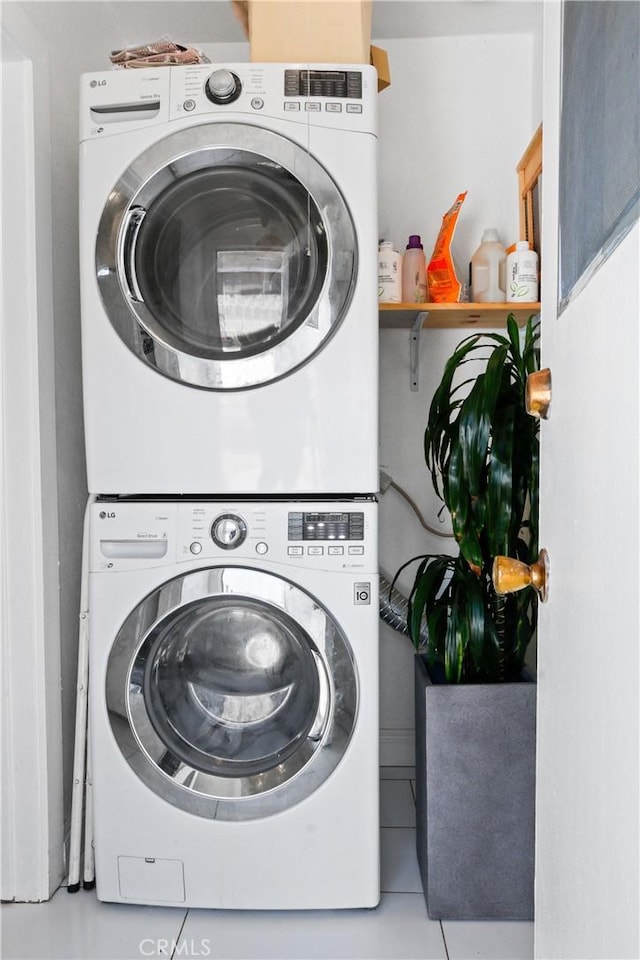 laundry room featuring tile patterned floors and stacked washing maching and dryer