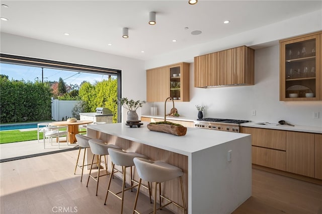 kitchen with modern cabinets, stainless steel gas stovetop, a center island, light countertops, and a breakfast bar area