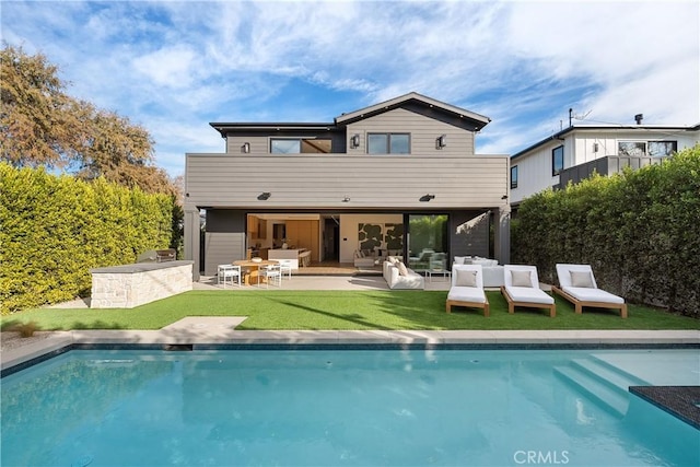 back of house featuring a yard, an outdoor pool, outdoor lounge area, and a patio area