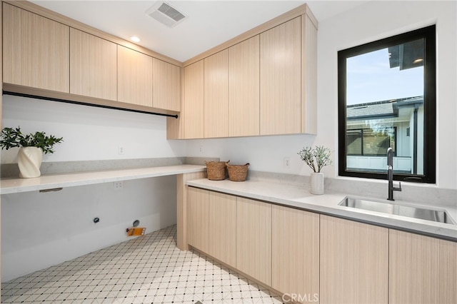 laundry room featuring visible vents, a sink, light floors, and cabinet space