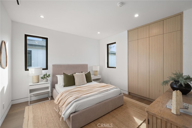 bedroom with recessed lighting, light wood-type flooring, and baseboards