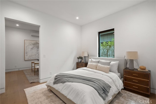 bedroom featuring recessed lighting, a wall mounted AC, and wood finished floors