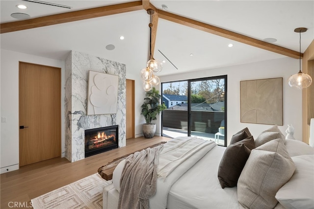 bedroom with recessed lighting, access to exterior, wood finished floors, vaulted ceiling with beams, and a premium fireplace