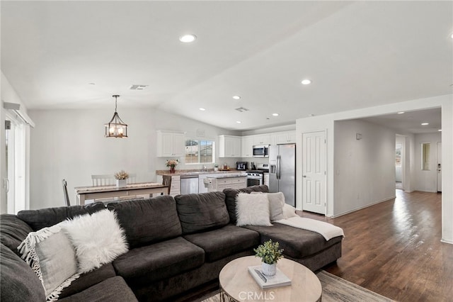 living room featuring vaulted ceiling, hardwood / wood-style floors, and an inviting chandelier