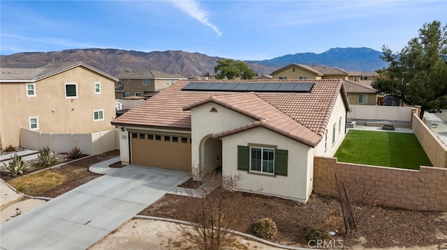 view of front of property featuring a garage, a mountain view, and solar panels