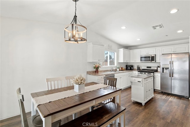 kitchen with stainless steel appliances, a center island, hanging light fixtures, and white cabinets