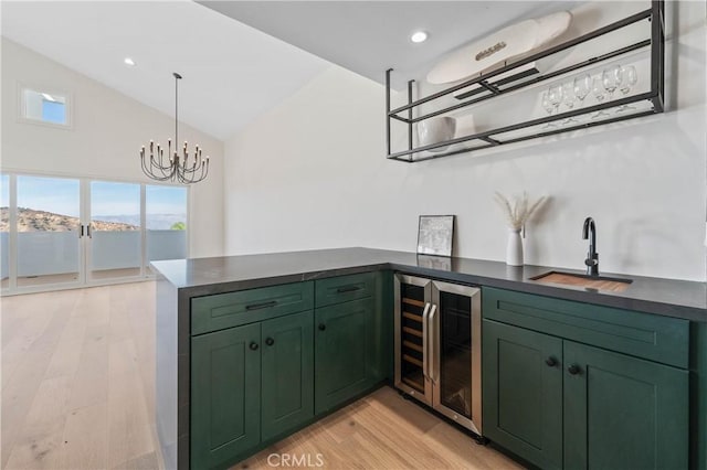 kitchen featuring vaulted ceiling, green cabinets, decorative light fixtures, wine cooler, and sink