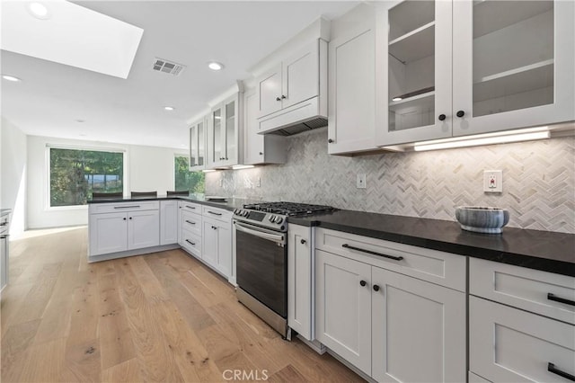 kitchen featuring gas stove, white cabinets, a skylight, and light wood-type flooring