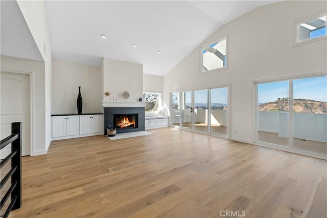 unfurnished living room with high vaulted ceiling and light wood-type flooring