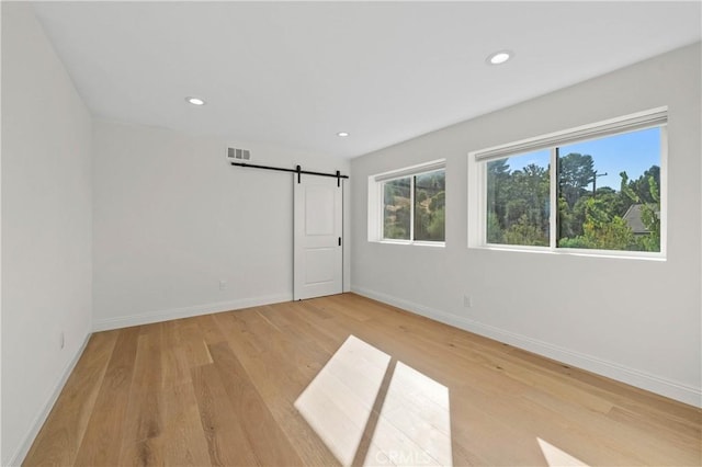 spare room with light hardwood / wood-style flooring and a barn door