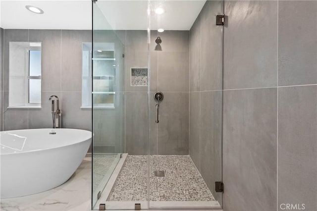 bathroom featuring tile walls and shower with separate bathtub