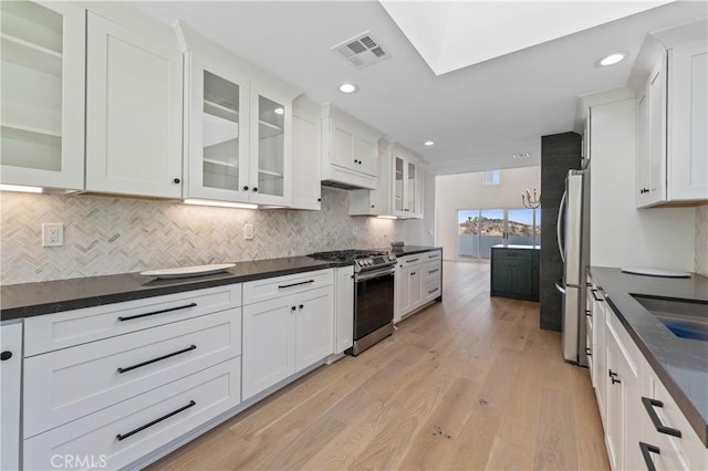 kitchen featuring light wood-type flooring, appliances with stainless steel finishes, a skylight, and white cabinetry