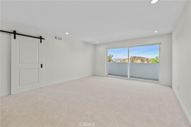 empty room with light colored carpet and a barn door