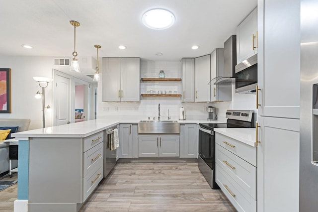 kitchen featuring sink, decorative light fixtures, kitchen peninsula, backsplash, and appliances with stainless steel finishes