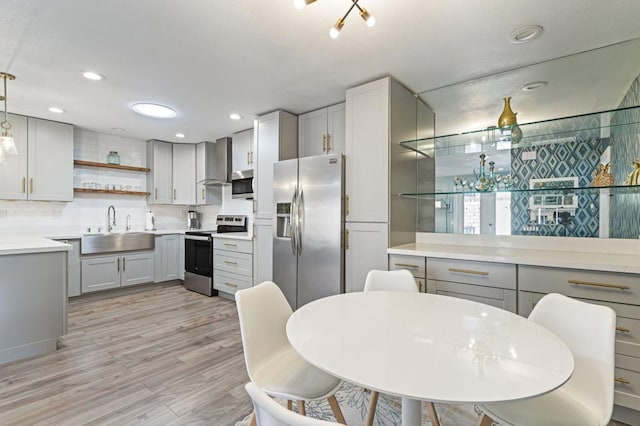 kitchen with gray cabinetry, stainless steel appliances, light wood-type flooring, sink, and decorative light fixtures