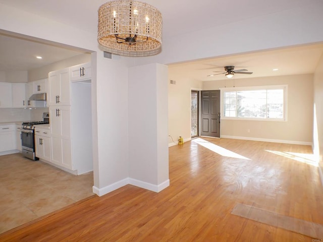 empty room with light hardwood / wood-style floors and ceiling fan with notable chandelier