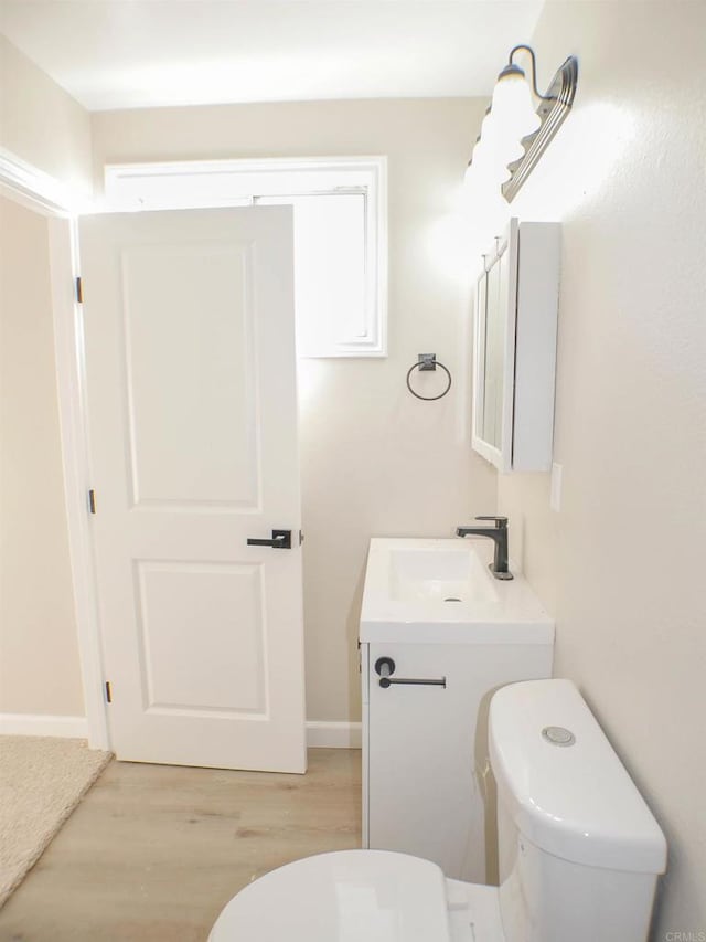 bathroom featuring toilet, vanity, and hardwood / wood-style flooring