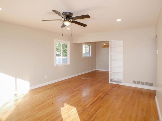 spare room featuring light hardwood / wood-style floors and ceiling fan with notable chandelier