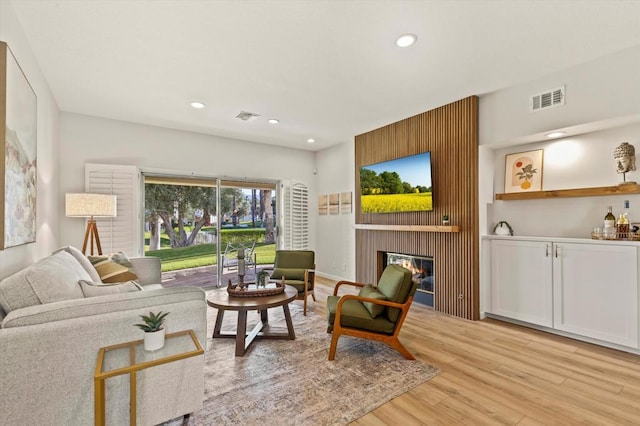 living room with a large fireplace and light hardwood / wood-style floors