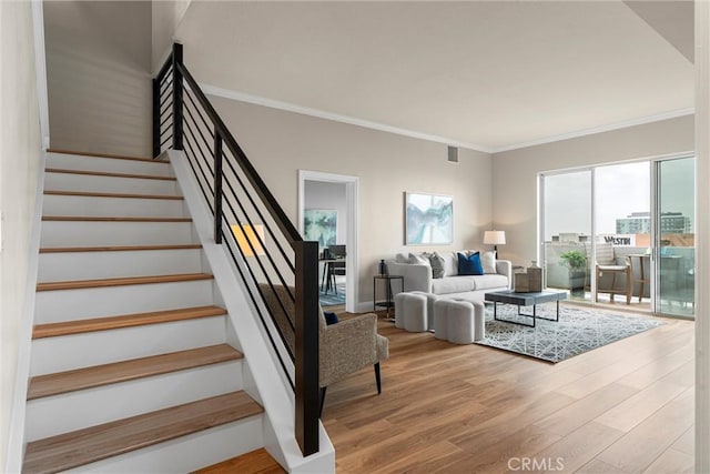 stairway with visible vents, ornamental molding, baseboards, and wood finished floors