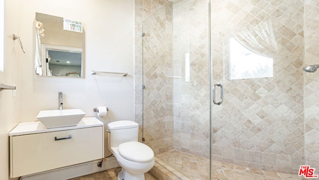 bathroom featuring a shower with door, vanity, and toilet