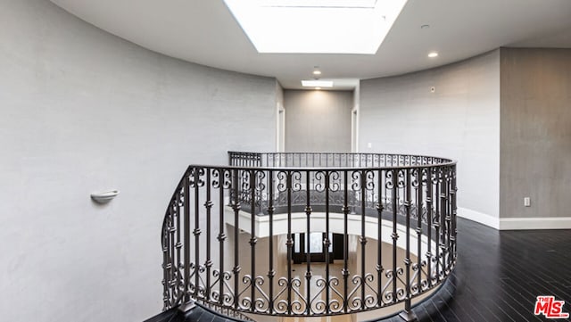 stairway with hardwood / wood-style floors and a skylight