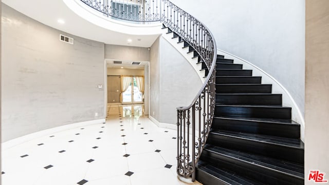 stairs featuring a towering ceiling and tile patterned floors