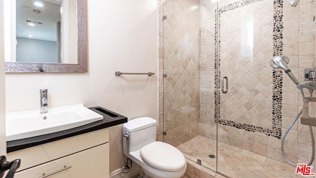 bathroom featuring vanity, toilet, and a shower with shower door