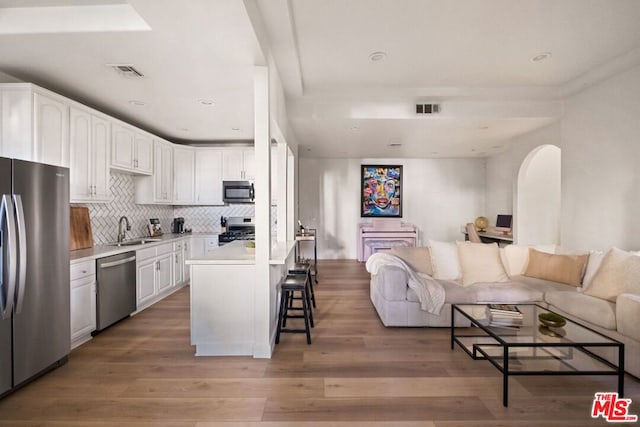 kitchen with stainless steel appliances, a center island, a breakfast bar area, and white cabinetry