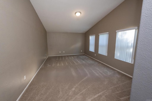 empty room featuring vaulted ceiling and dark carpet