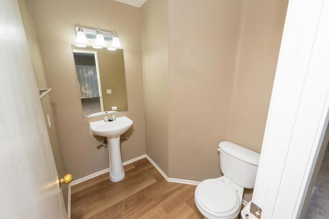 bathroom featuring toilet, sink, and hardwood / wood-style flooring