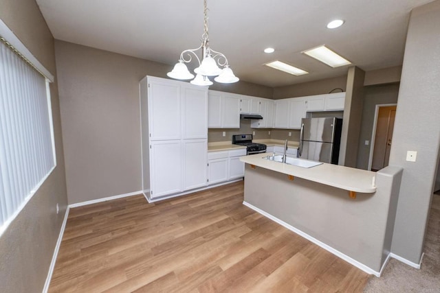 kitchen featuring a notable chandelier, appliances with stainless steel finishes, white cabinetry, and hanging light fixtures