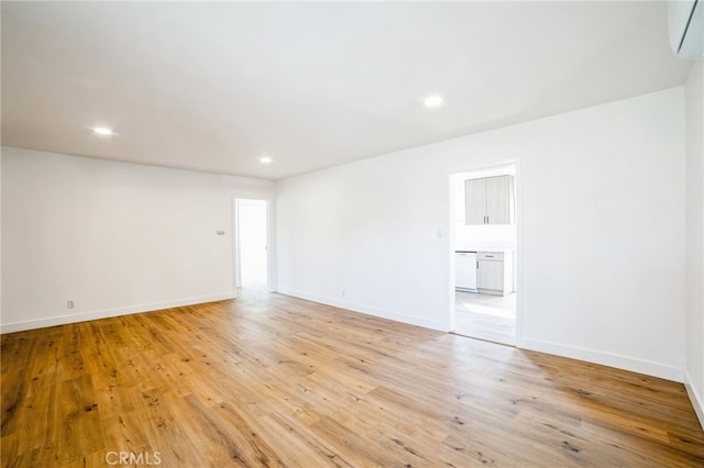 unfurnished room with a wall mounted AC and light hardwood / wood-style flooring