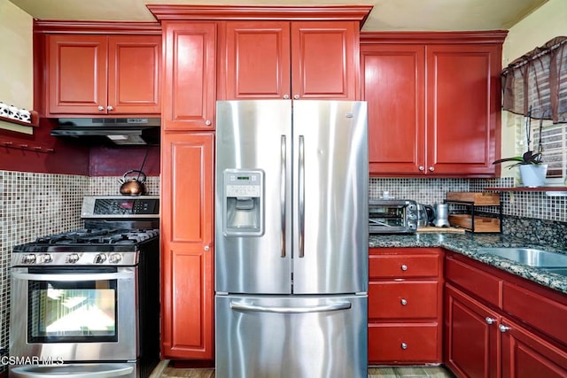 kitchen with exhaust hood, appliances with stainless steel finishes, dark stone countertops, and decorative backsplash