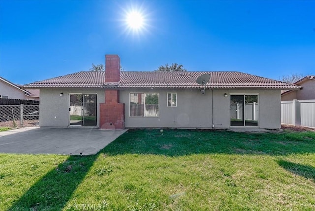 back of property with a lawn and a patio