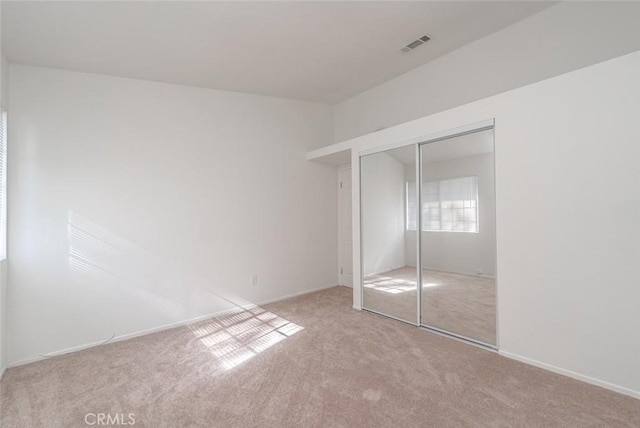 unfurnished bedroom with a closet and light carpet