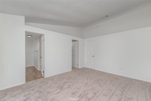 unfurnished room with vaulted ceiling and light carpet