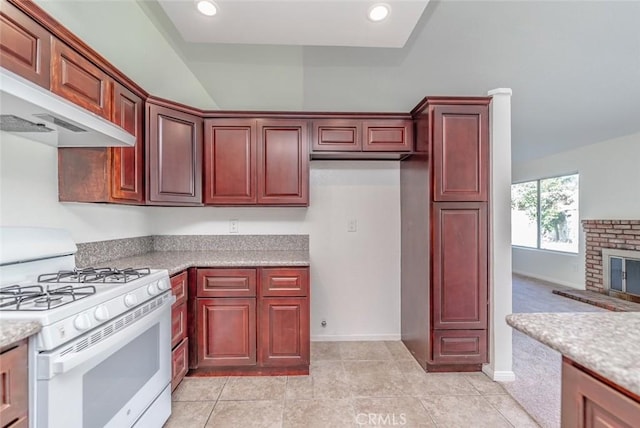 kitchen with a fireplace, wall chimney exhaust hood, light tile patterned floors, gas range gas stove, and light stone countertops